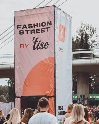 Kuvassa mainosteline, johon kiinnitetty Tise verkkomyyntialustan vaalea mainoslakana, jossa brändin logo ja teksti Fashion Street